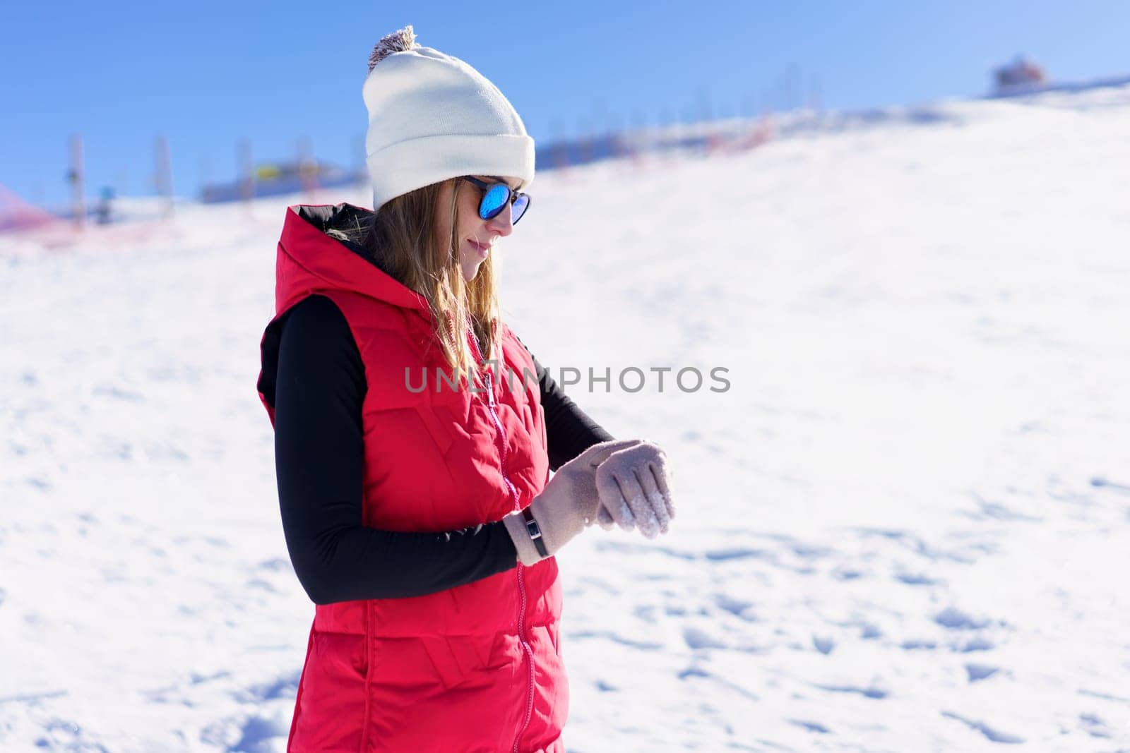 Happy young woman standing and checking time on wristwatch by javiindy