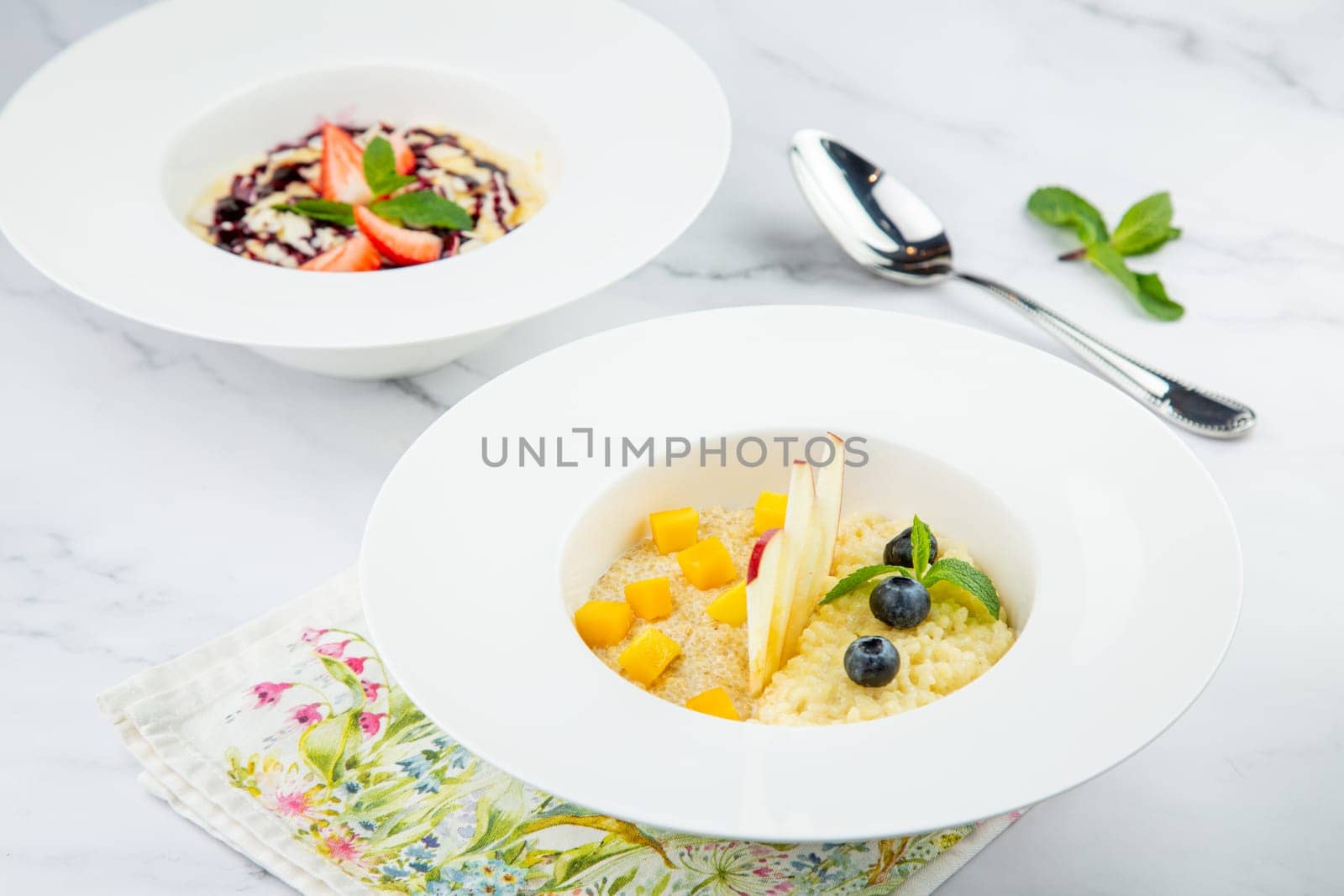 porridge with strawberries, mint and berry jam in a white plate