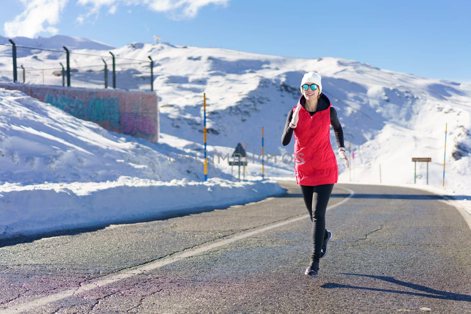 Young woman running on road near snow and warming up by javiindy