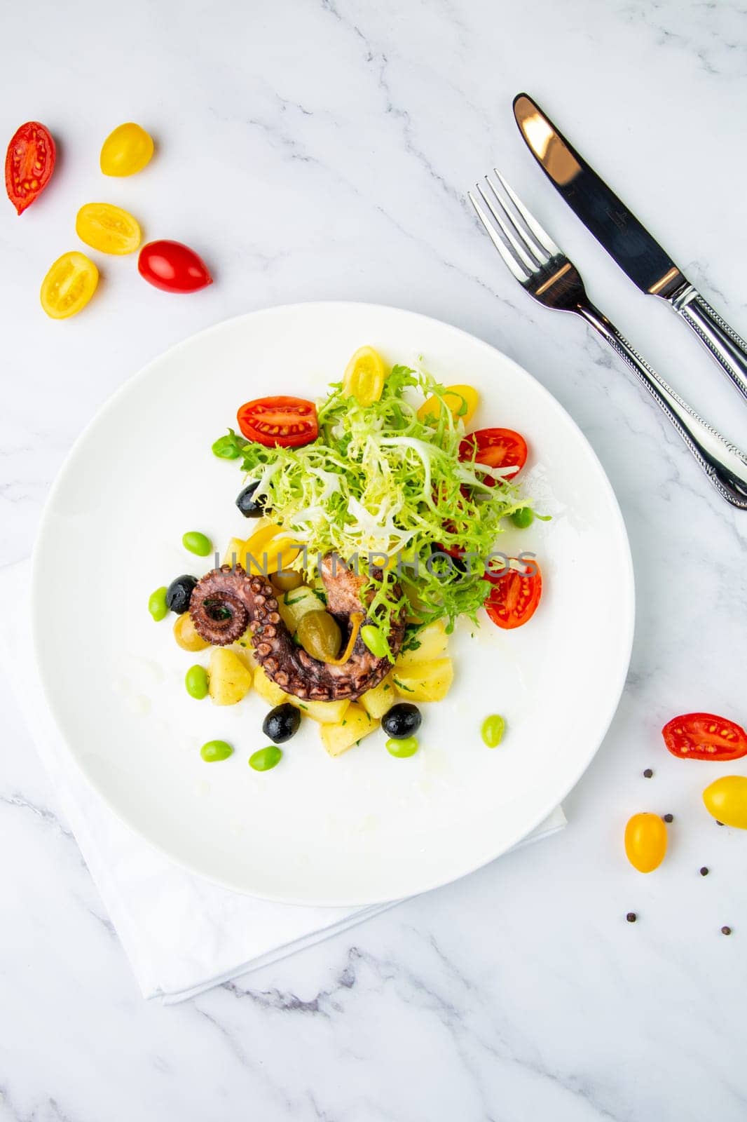 salad with olives, herbs, cherry tomatoes, potatoes and octopus tentacles