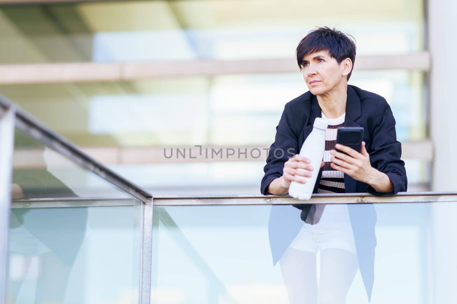 Women with smartphone and white bottle of water by javiindy