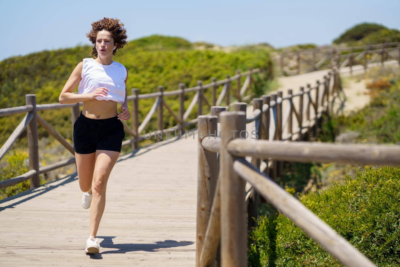 Sportive woman running along walkway in countryside by javiindy