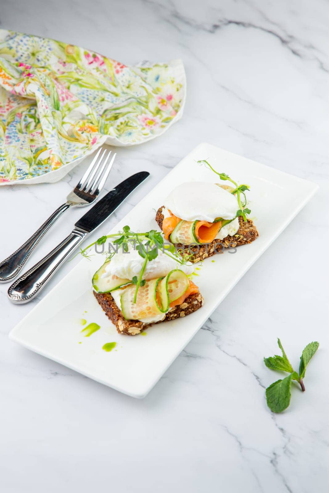 canapes on black bread with cheese, red fish, herbs and cucumber