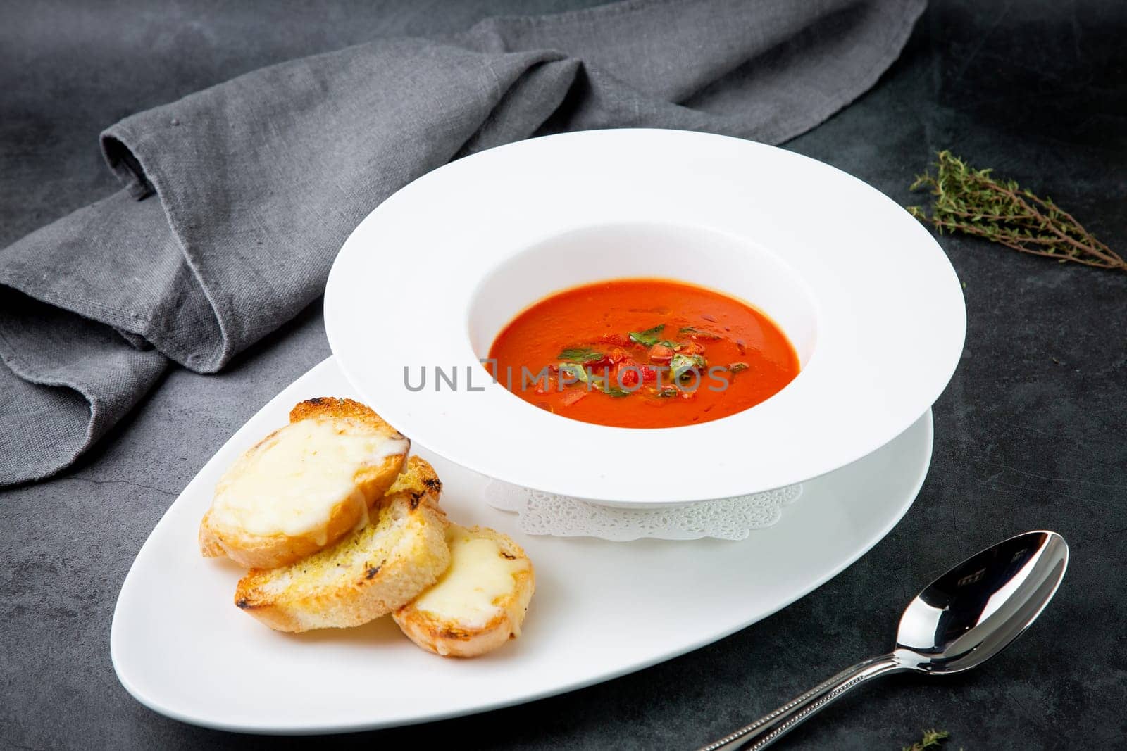 red tomato cream soup with herbs and toasted bread side view by tewolf