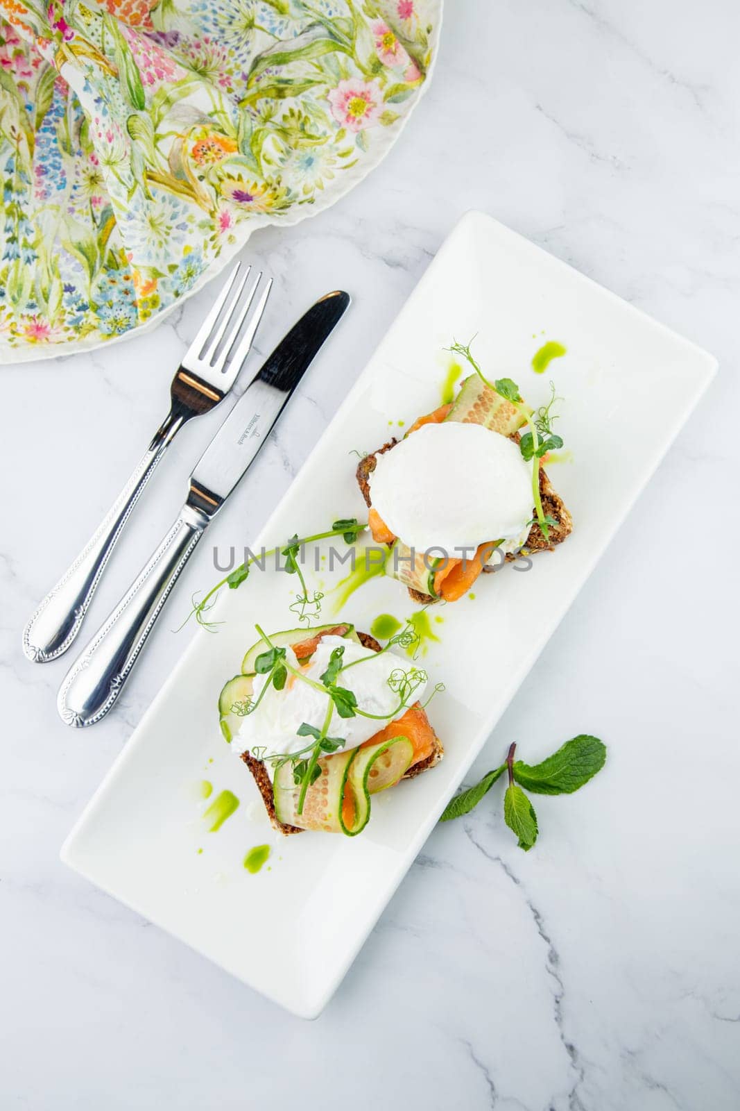 canapes on black bread with cheese, red fish, herbs and cucumber