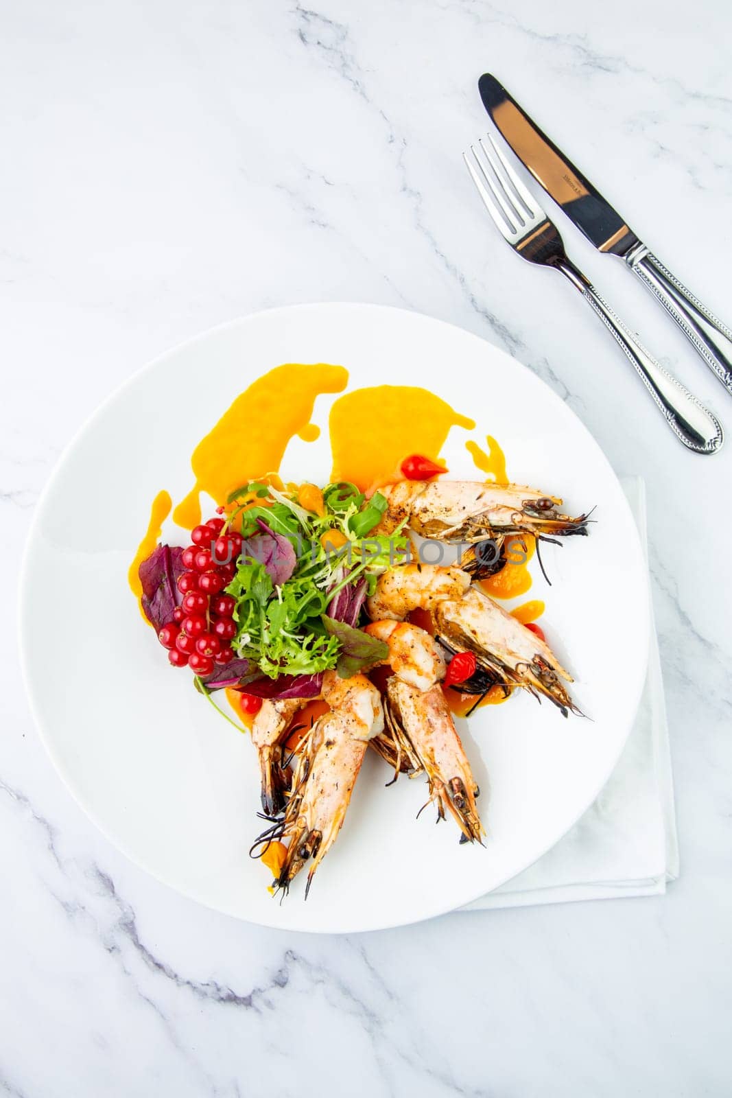 cooked shrimp with herbs and berries on a white plate