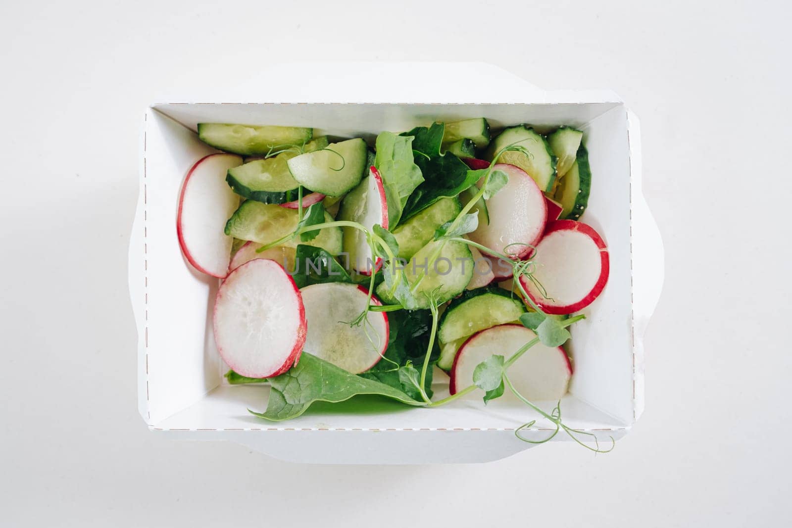 salad of radishes, herbs and cucumbers in a white container, top view by tewolf