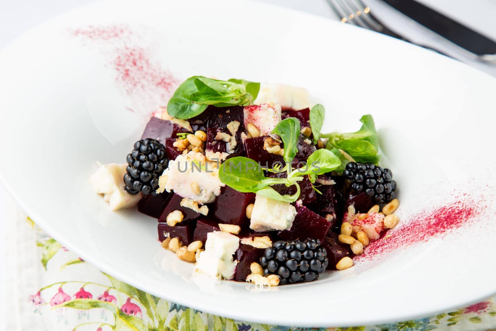 salad of blackberries, beets, seeds and cheese, side view on a white plate by tewolf