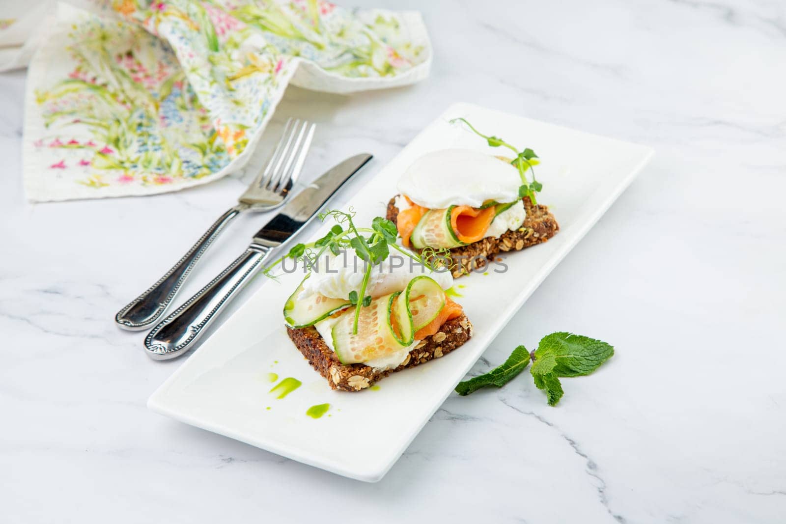 canapes on black bread with cheese, red fish, herbs and cucumber