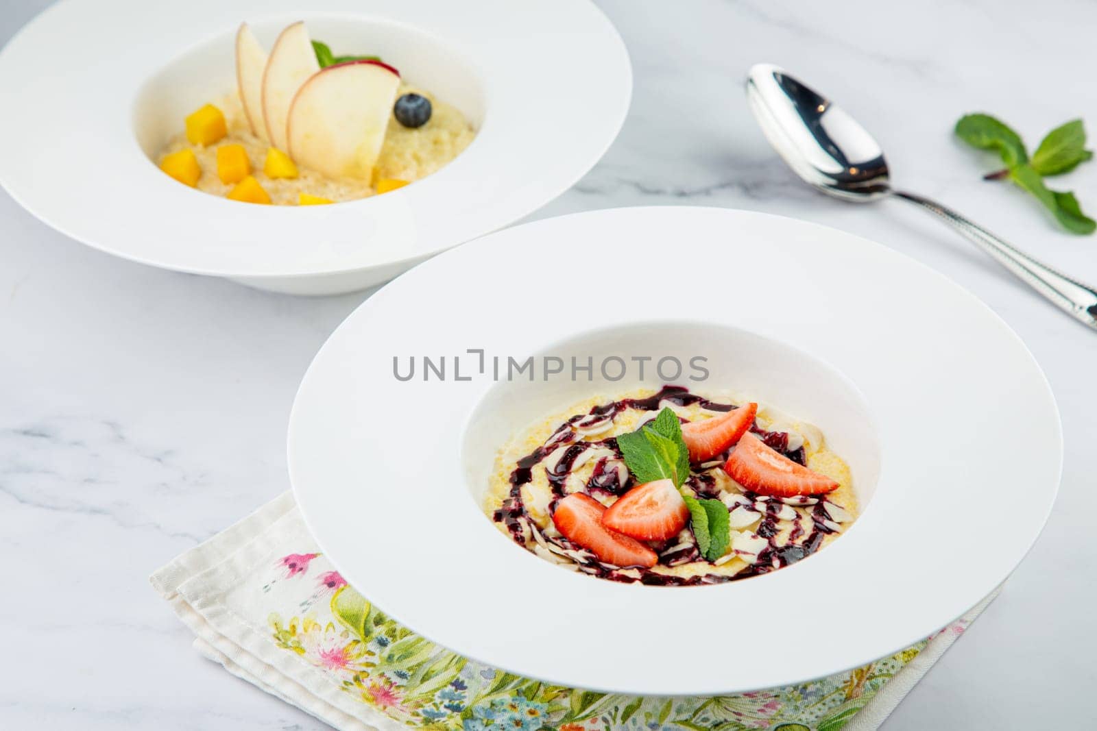 porridge with strawberries, mint and berry jam in a white plate