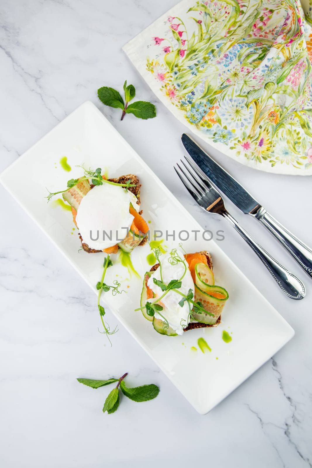 canapes on black bread with cheese, red fish, herbs and cucumber top view by tewolf