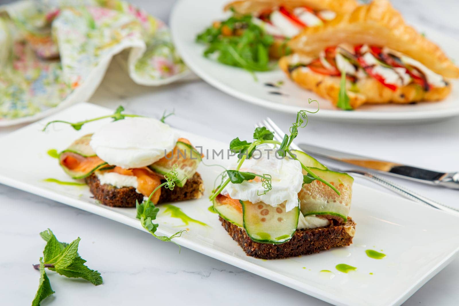 canapes on black bread with cheese, red fish, herbs and cucumber