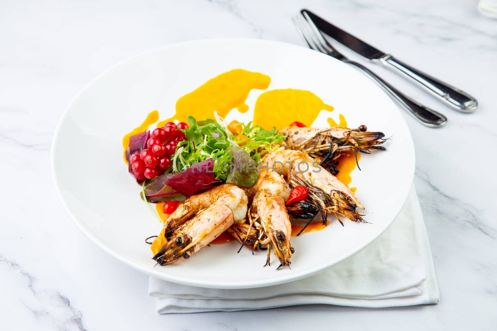 cooked shrimp with herbs and berries on a white plate, side view by tewolf