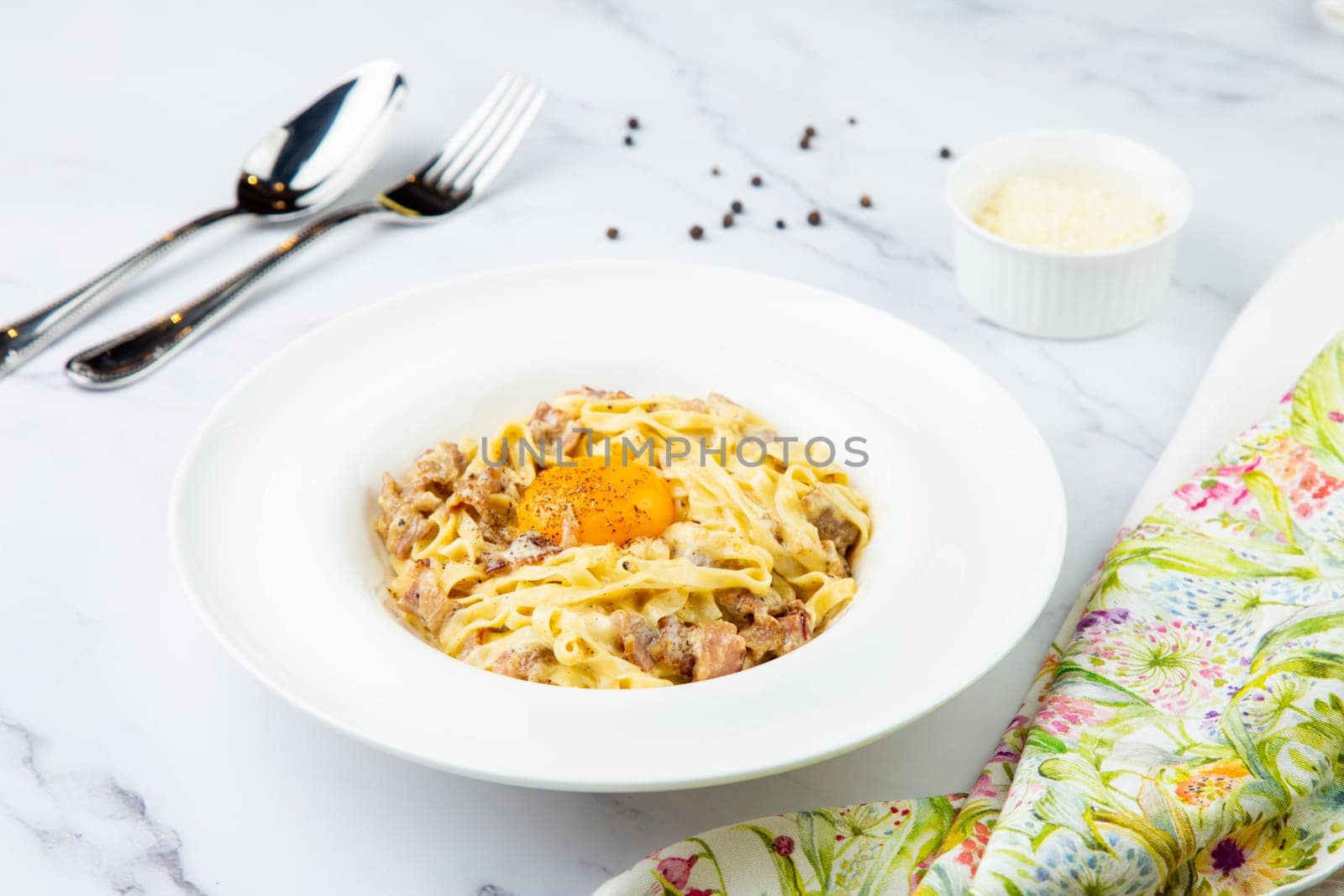 pasta in cream sauce with egg and black pepper on top side view by tewolf