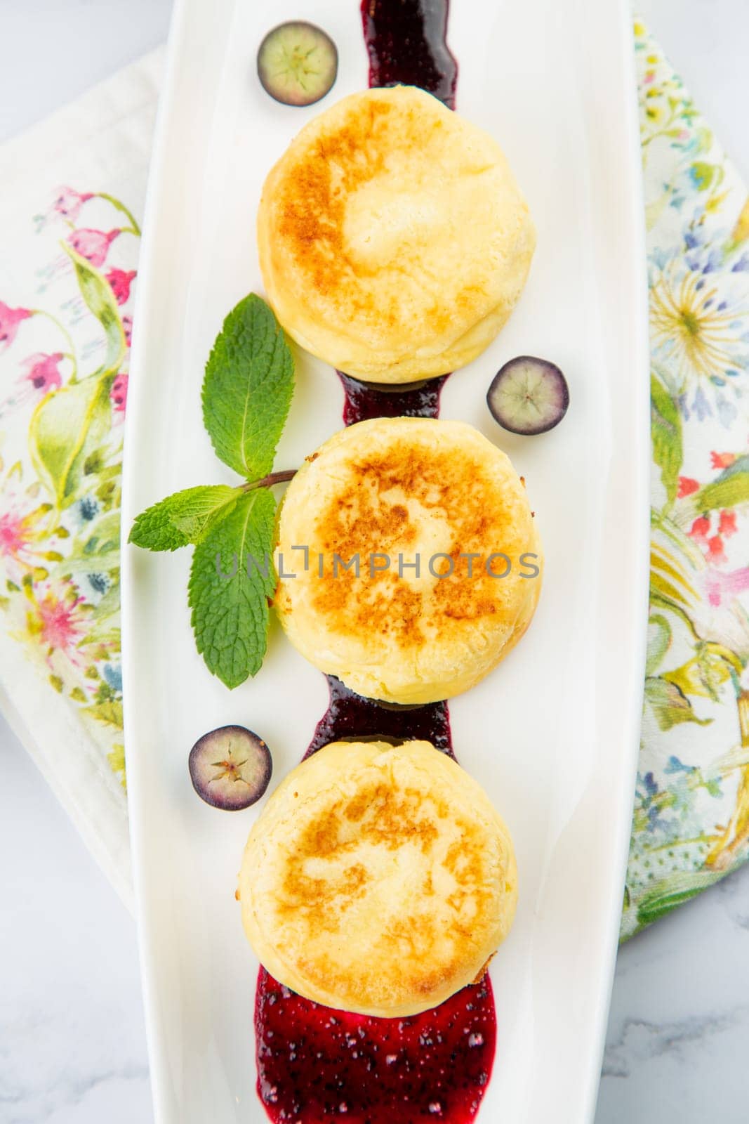 lush and tall cheesecakes with jam and mint on a white plate top view by tewolf