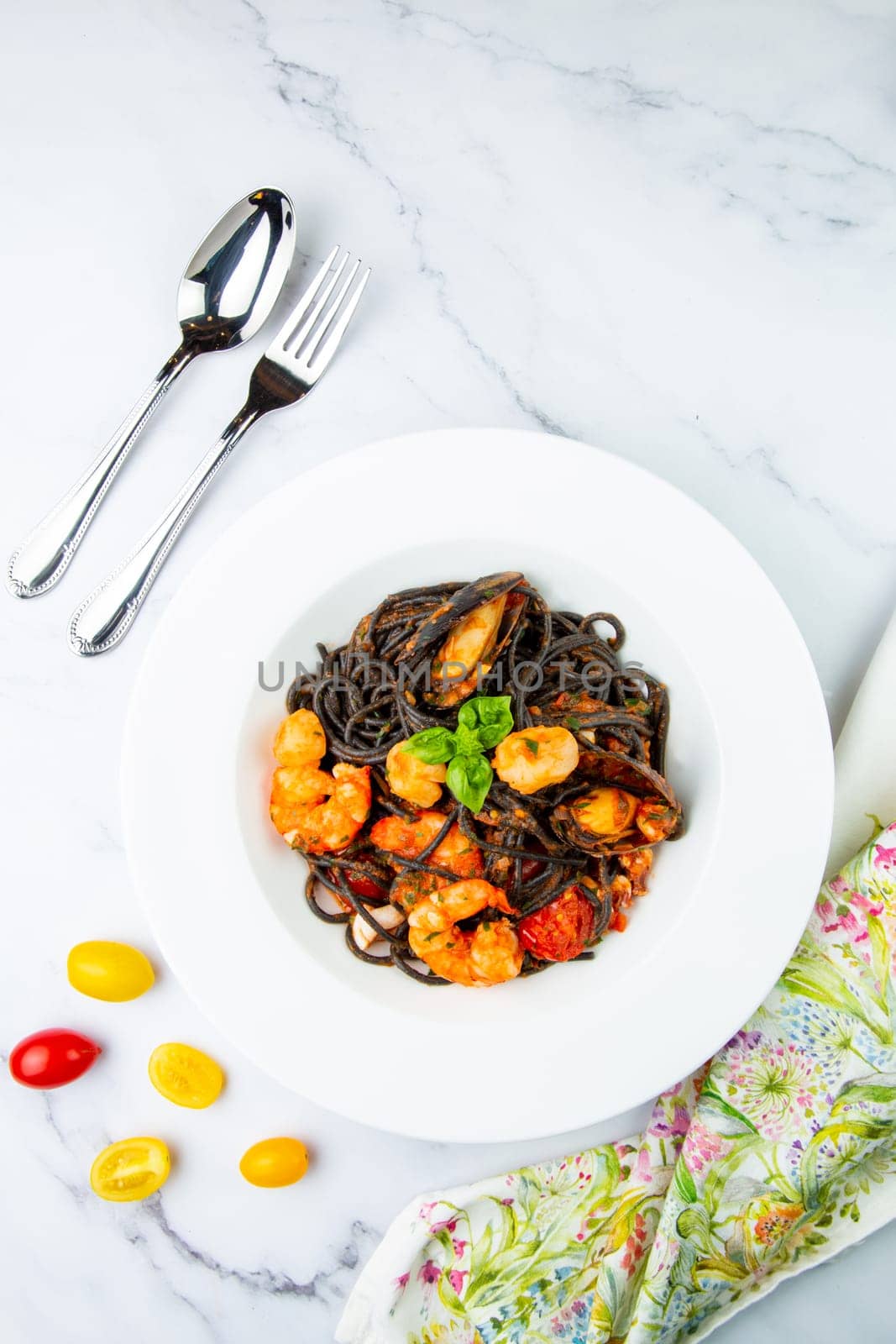 black noodles with mussels, shrimp, tomatoes and herbs