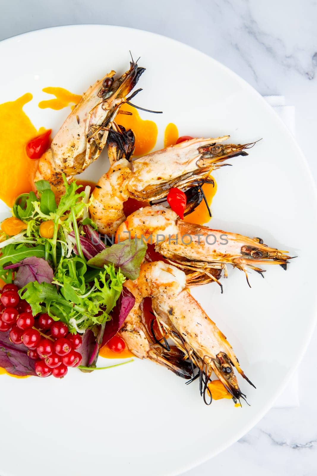 cooked shrimp with herbs and berries on a white plate, top view by tewolf