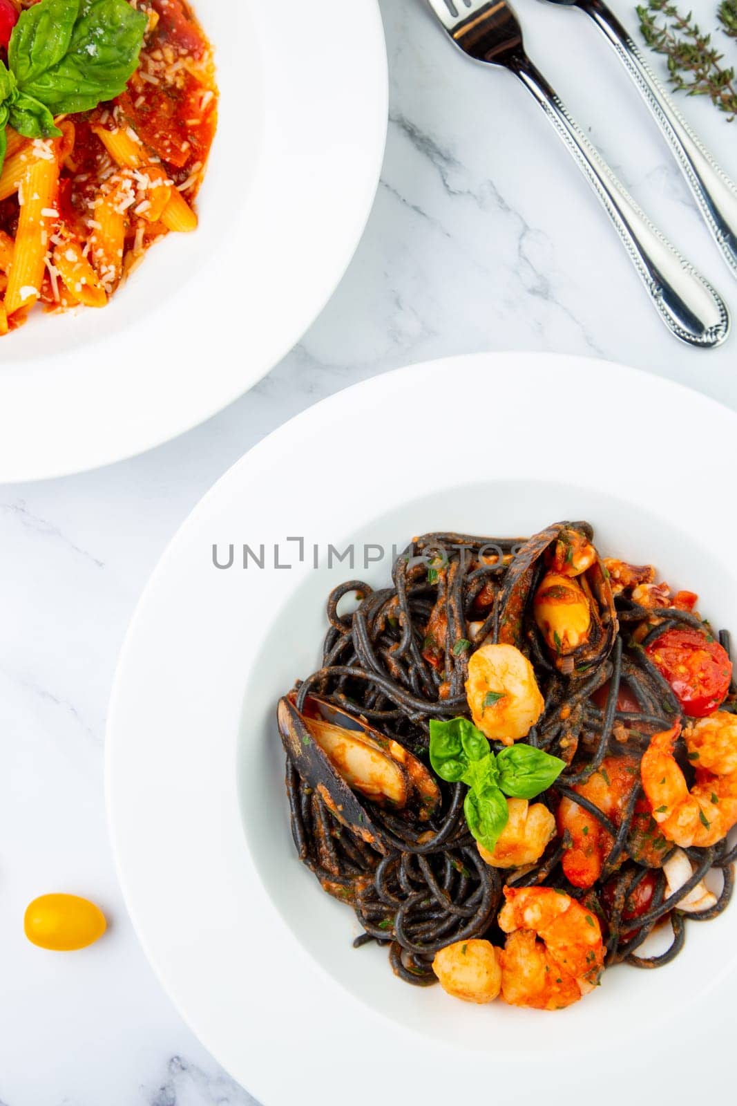 black noodles with mussels, shrimp, tomatoes and herbs top view by tewolf