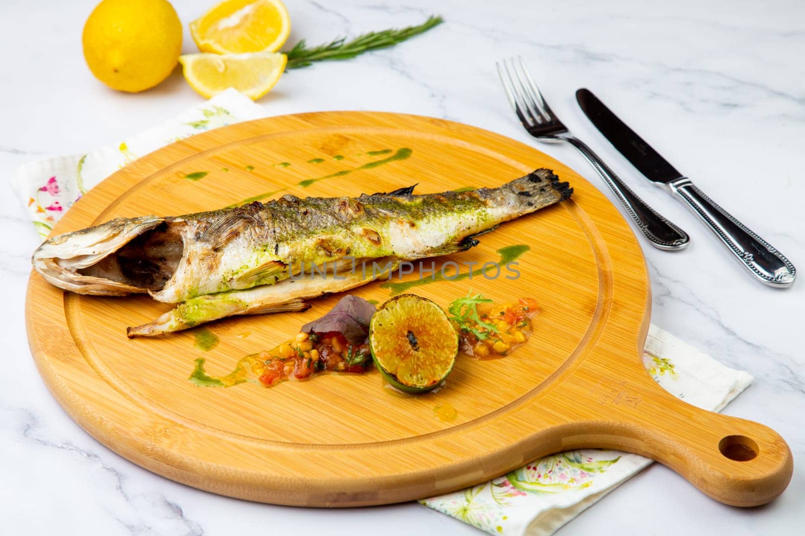 baked fish with spices and lemon on a wooden tray