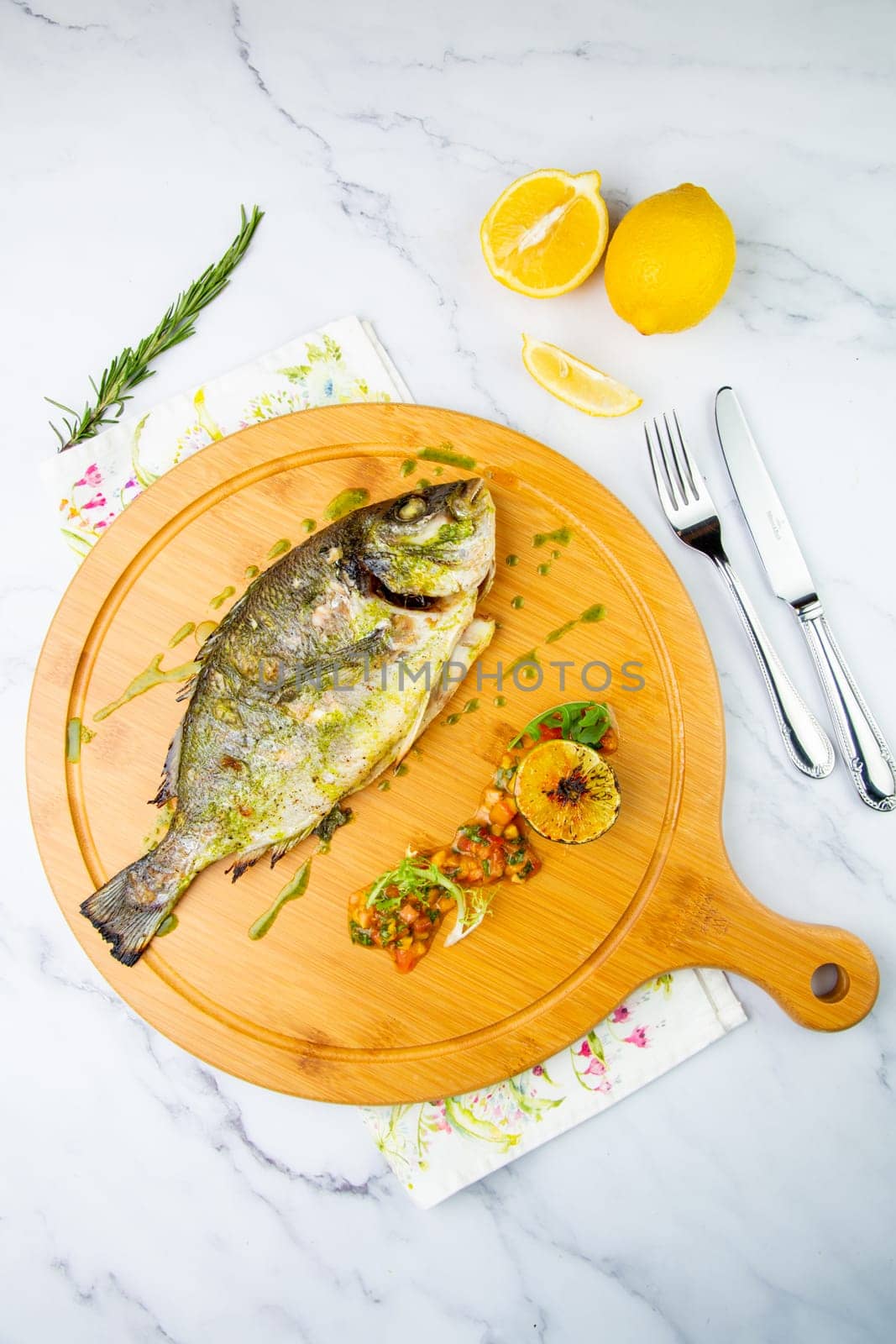 baked fish with spices and lemon on a wooden tray