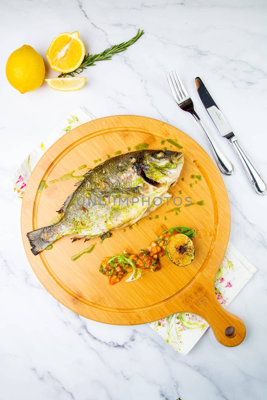 baked fish with spices and lemon on a wooden tray