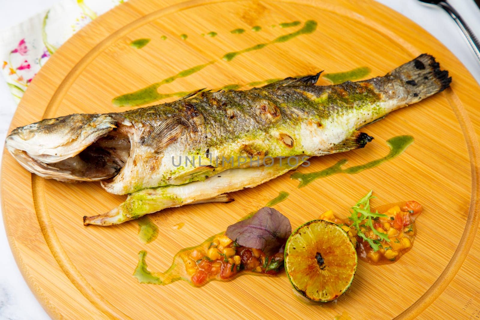 baked fish with spices and lemon on a wooden tray