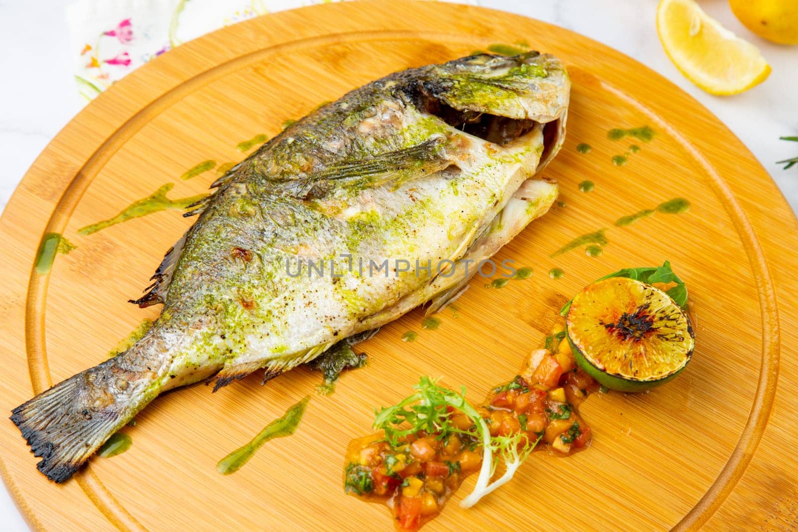 baked fish with spices and lemon on a wooden tray