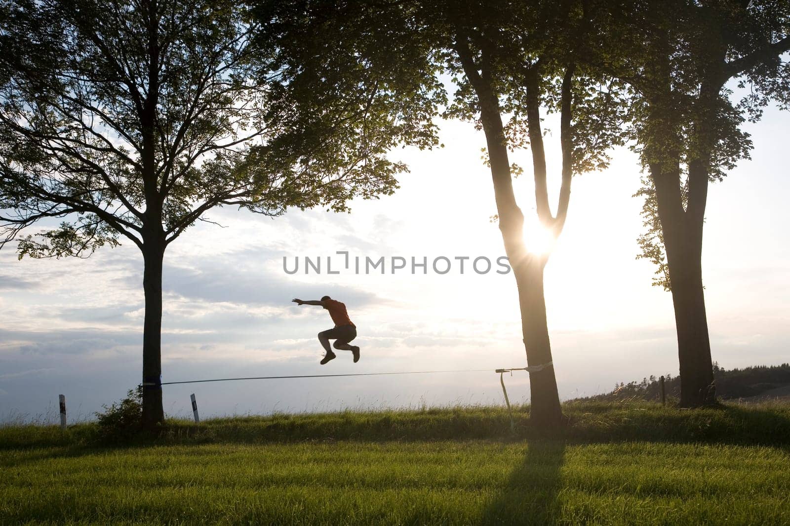 young man on the slackline in sunset