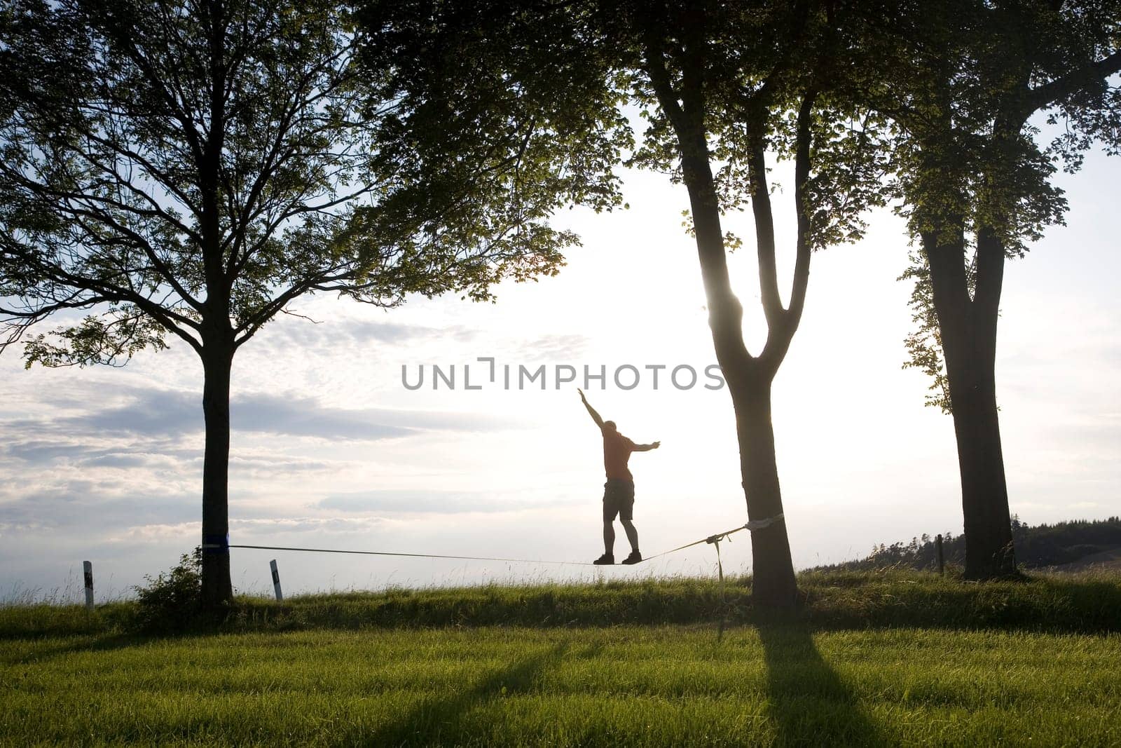 young man on the slackline in sunset