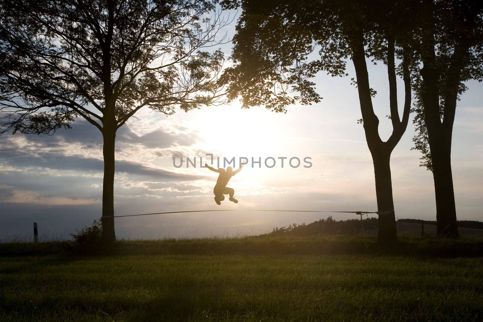 young man on the slackline in sunset