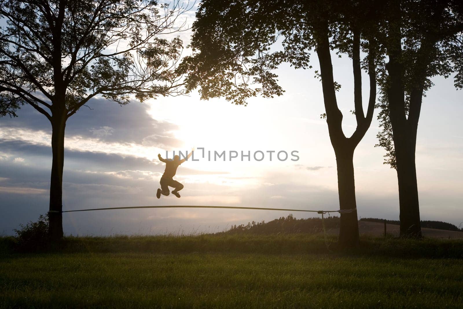 young man on the slackline in sunset