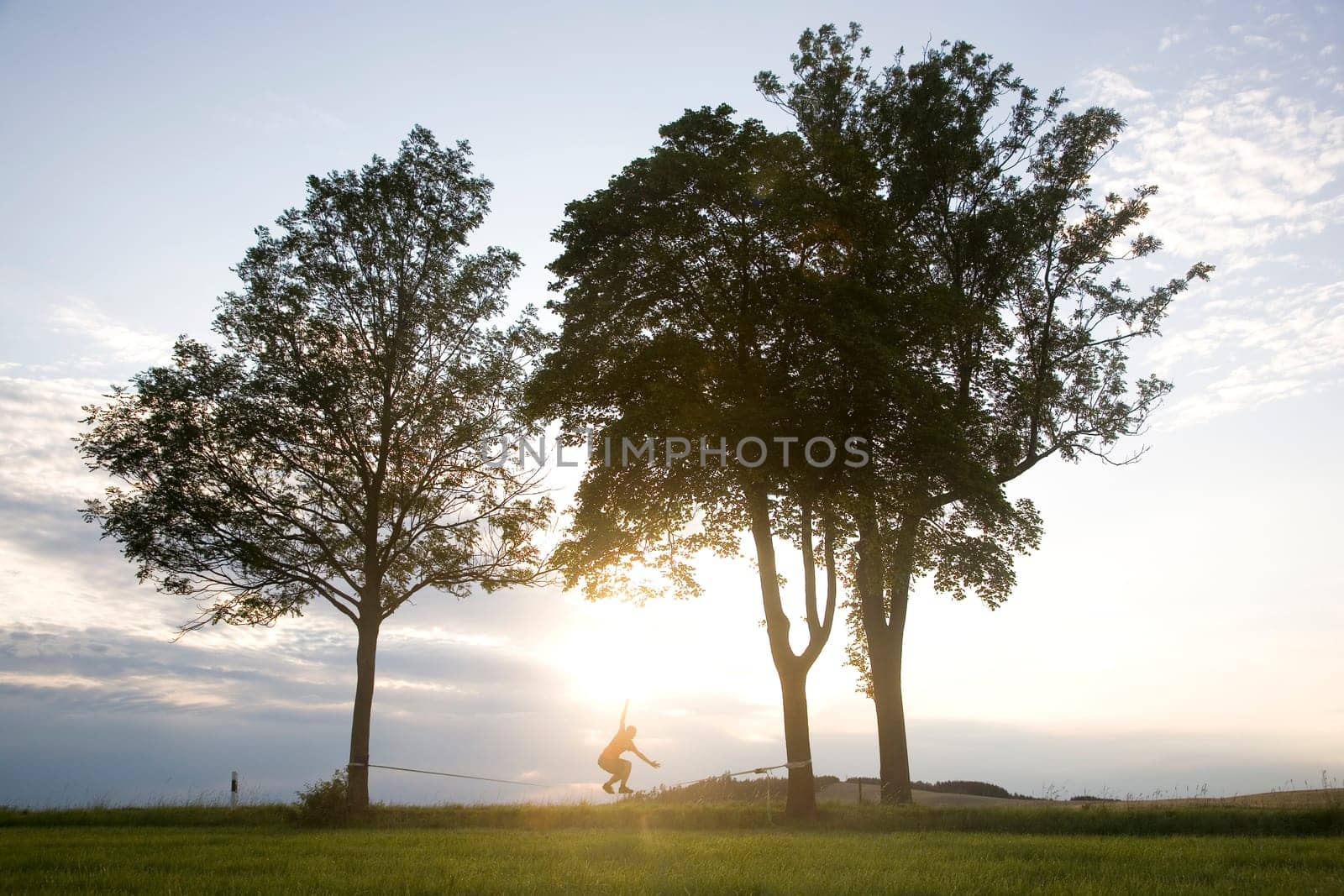 young man on the slackline in sunset