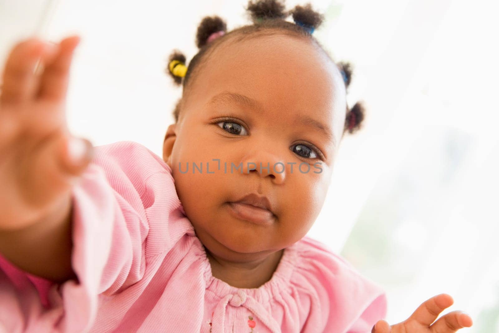 Baby indoors reaching hand out