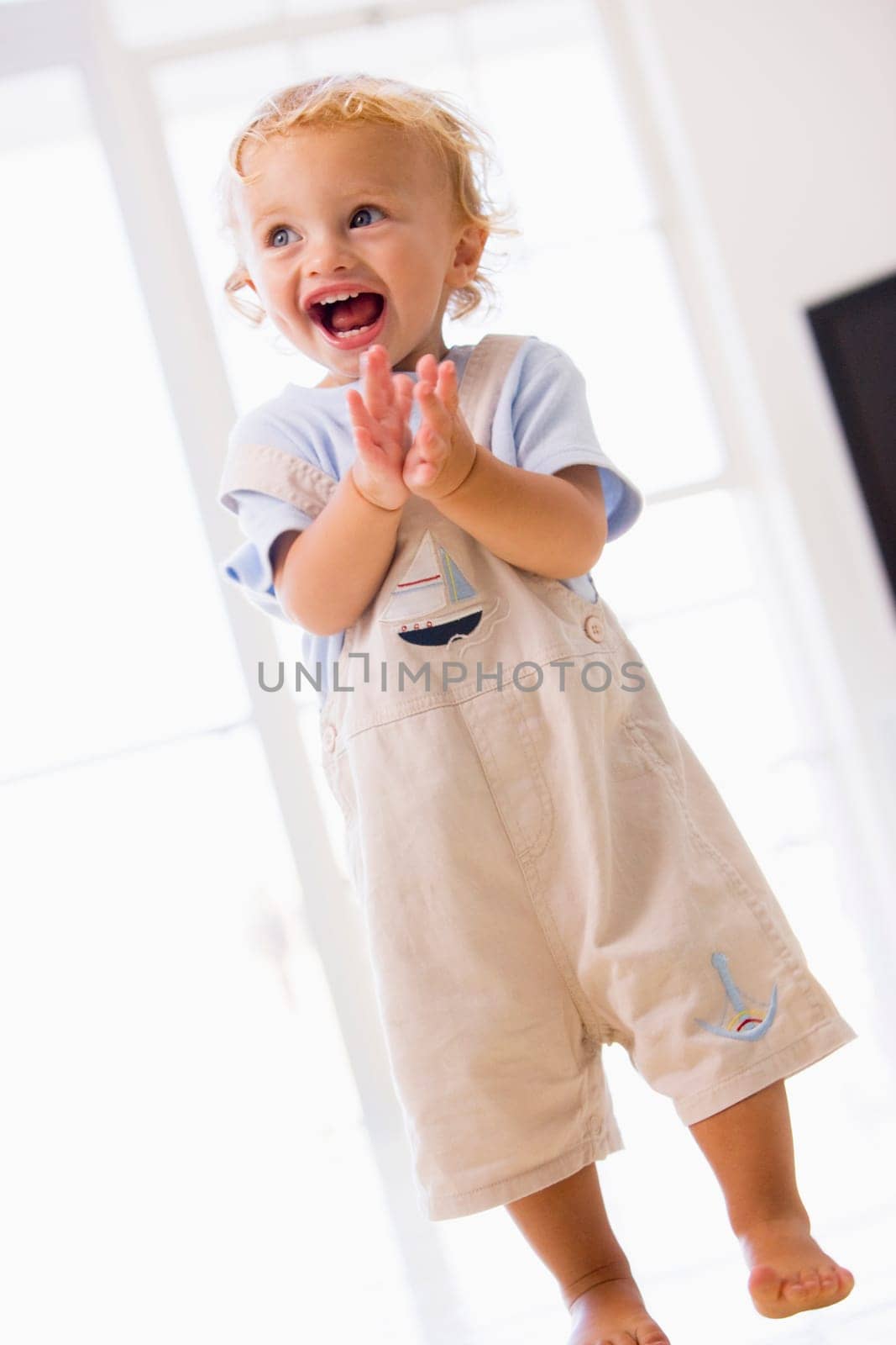 Young boy standing indoors applauding and smiling