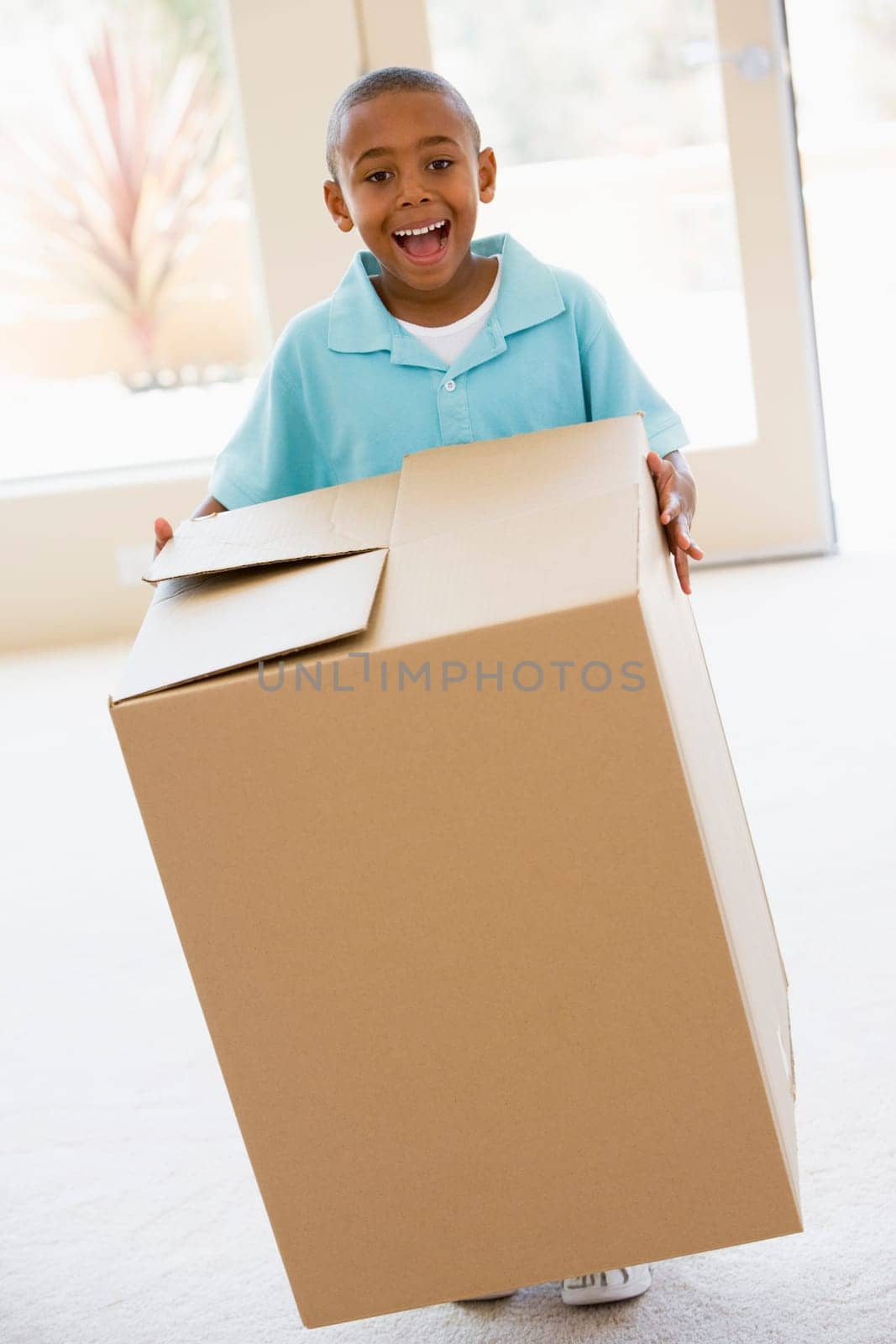 Young boy holding box in new home smiling