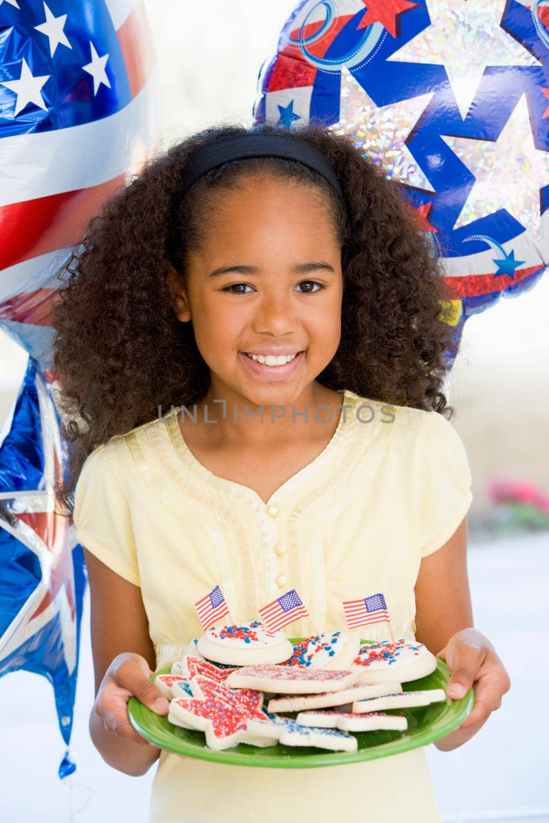 Young girl on fourth of July with balloons and cookies smiling
