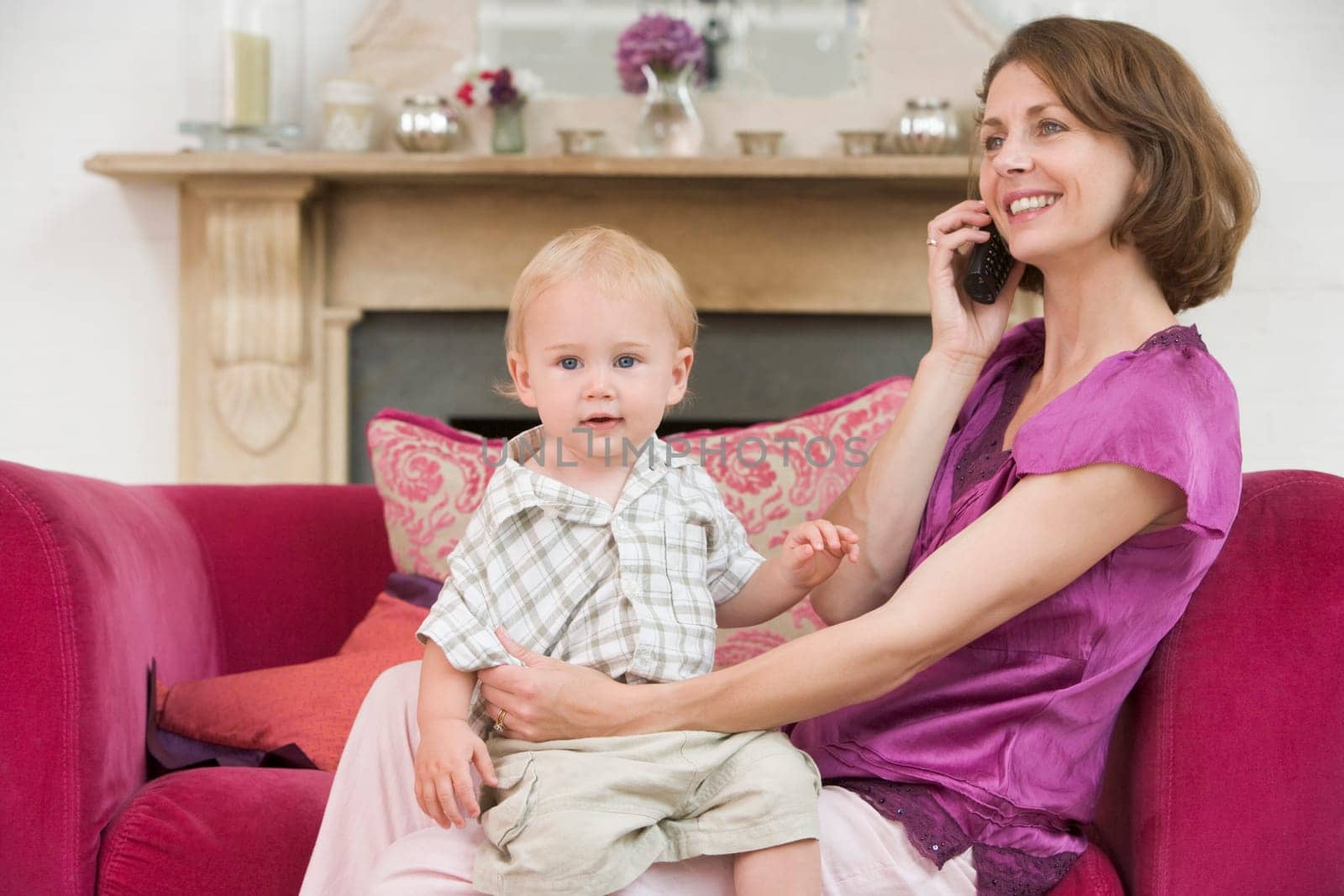 Mother using telephone in living room with baby smiling