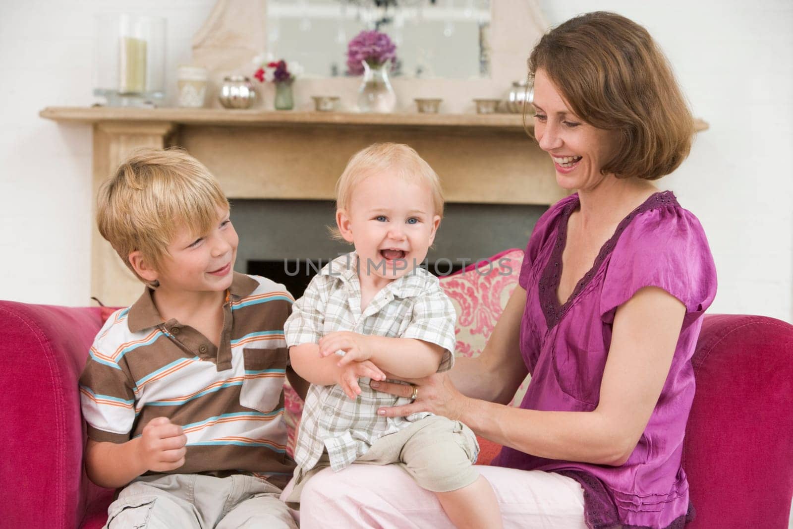 Mother in living room with baby and young boy smiling