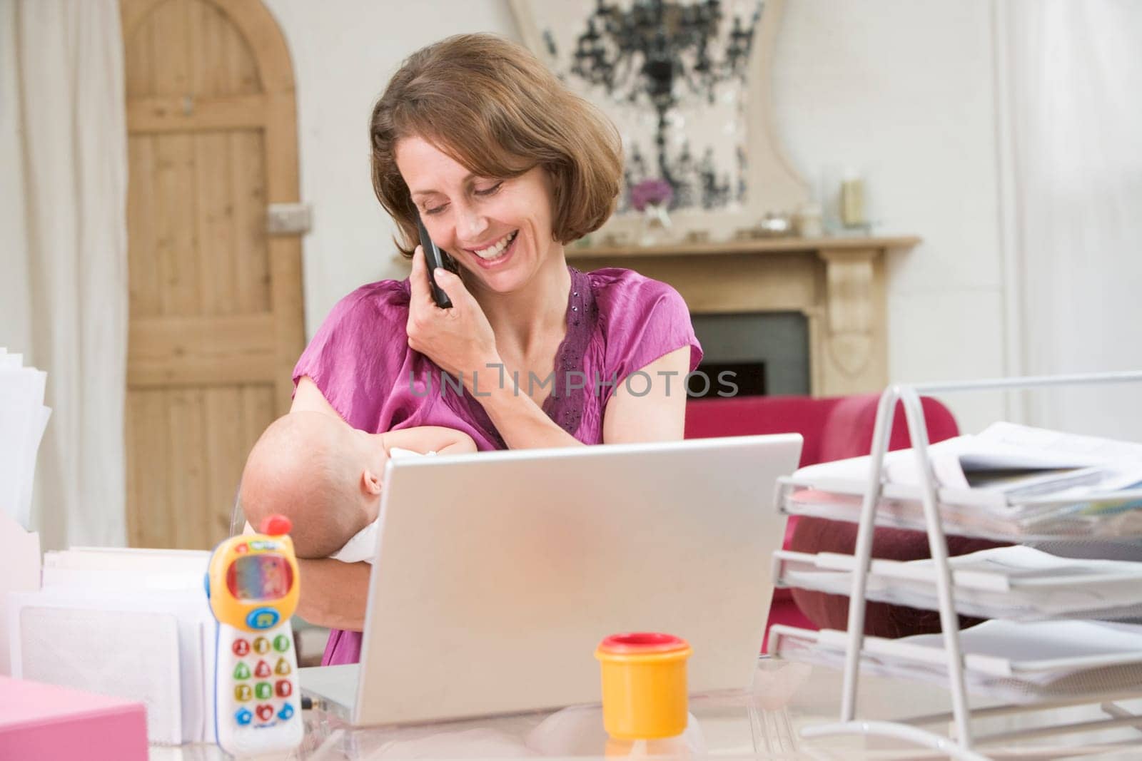 Mother and baby in home office with laptop and telephone
