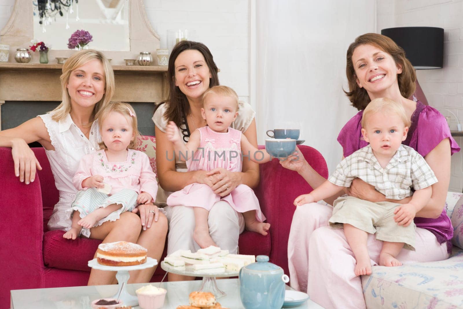 Three mothers in living room with babies and coffee smiling