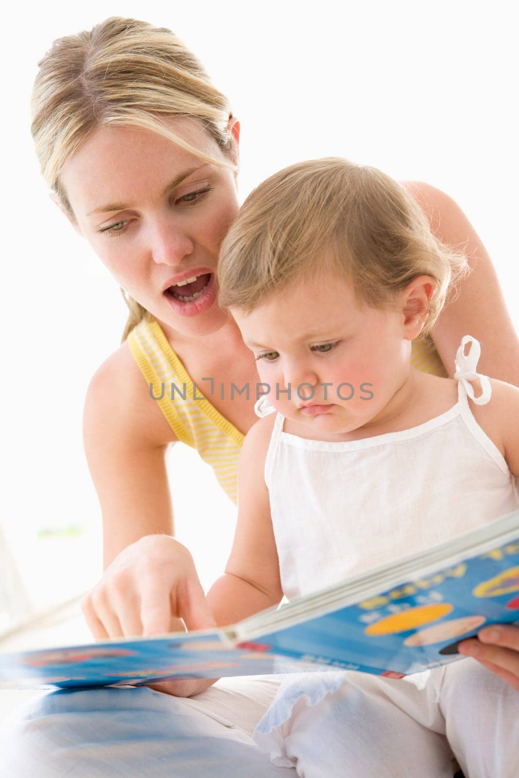 Mother and baby reading book indoors and pointing