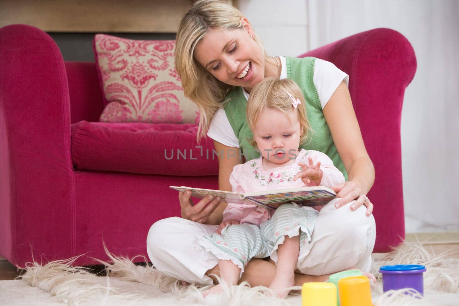 Mother in living room reading book with baby smiling