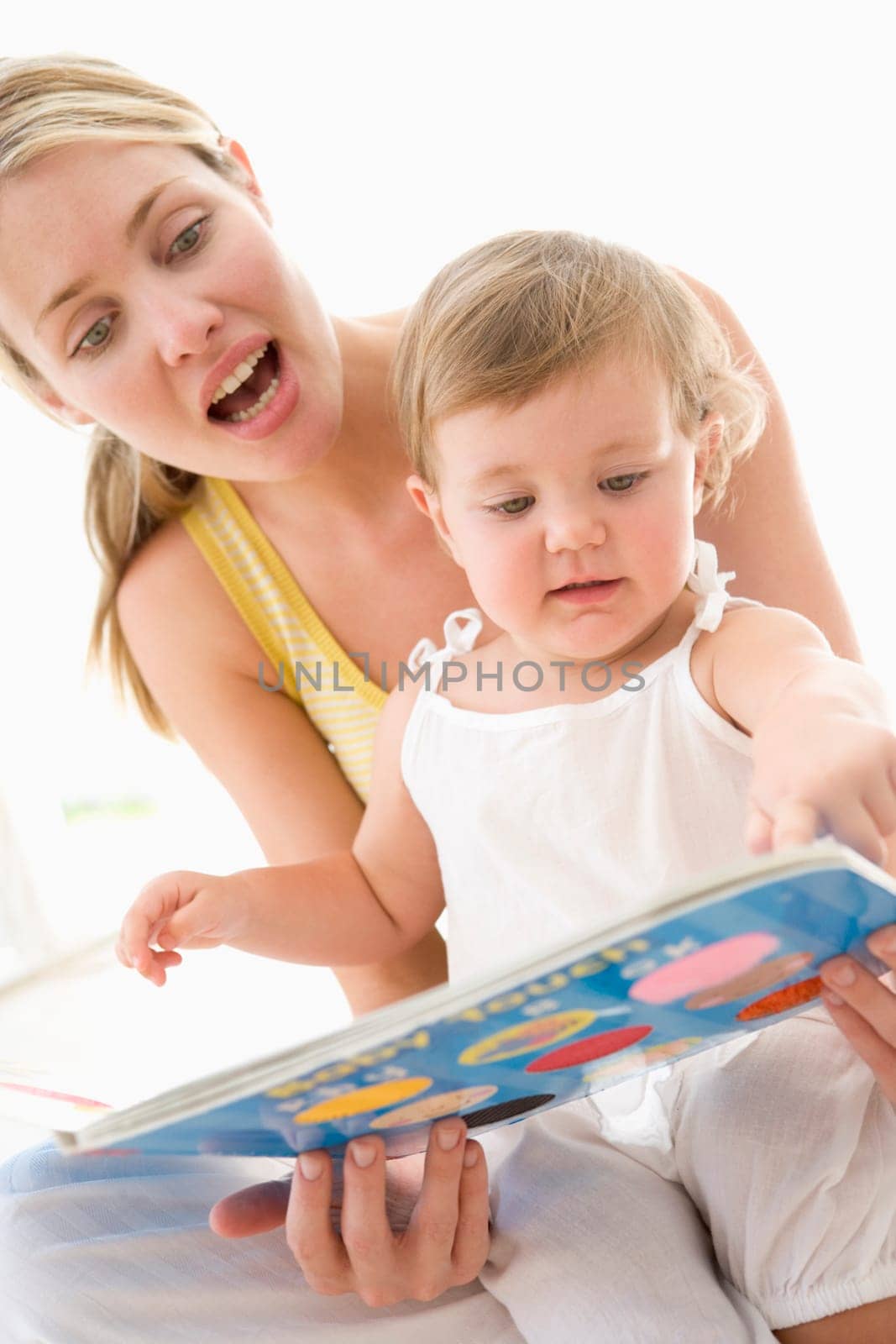 Mother and baby reading book indoors and pointing
