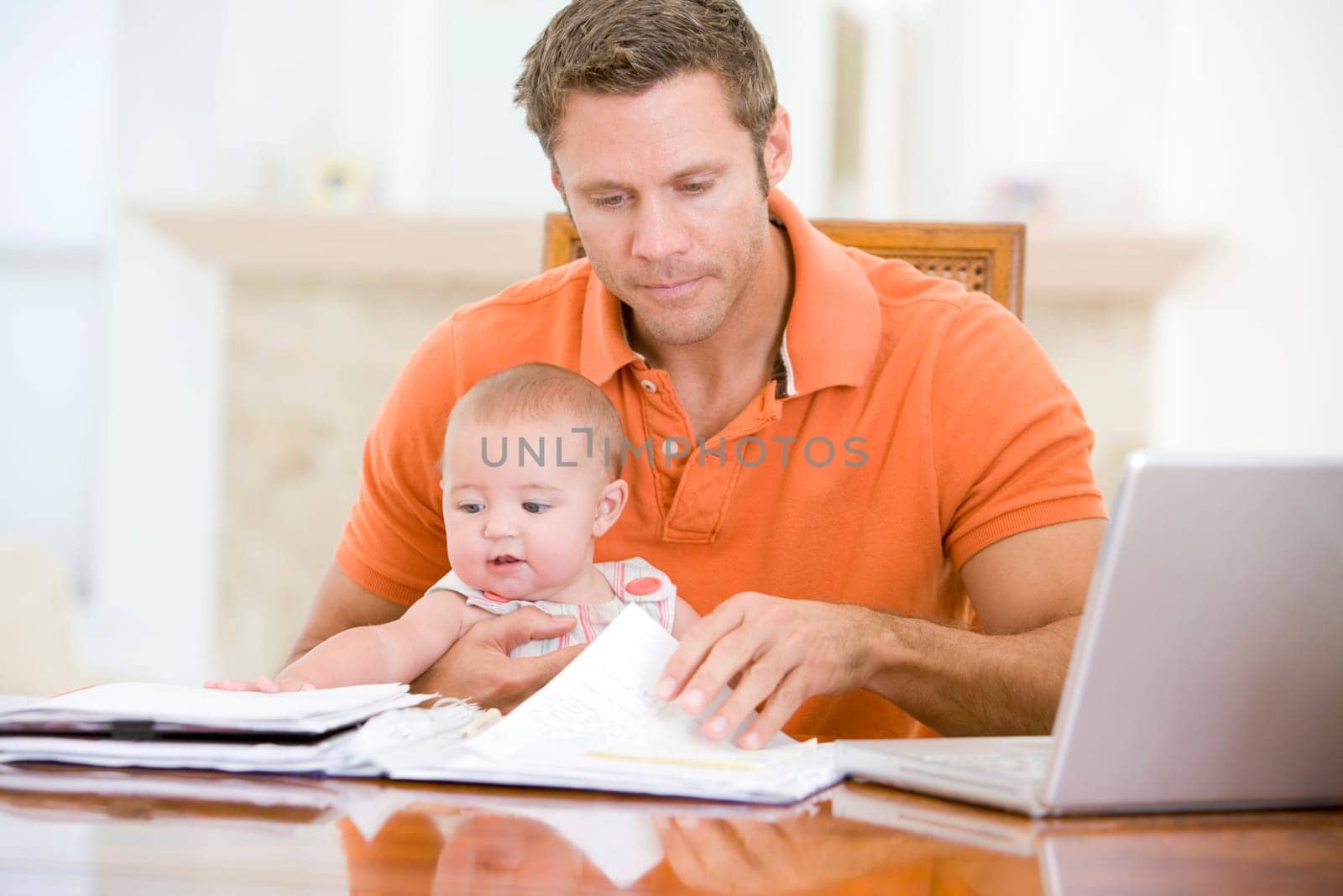 Father and baby in dining room with laptop