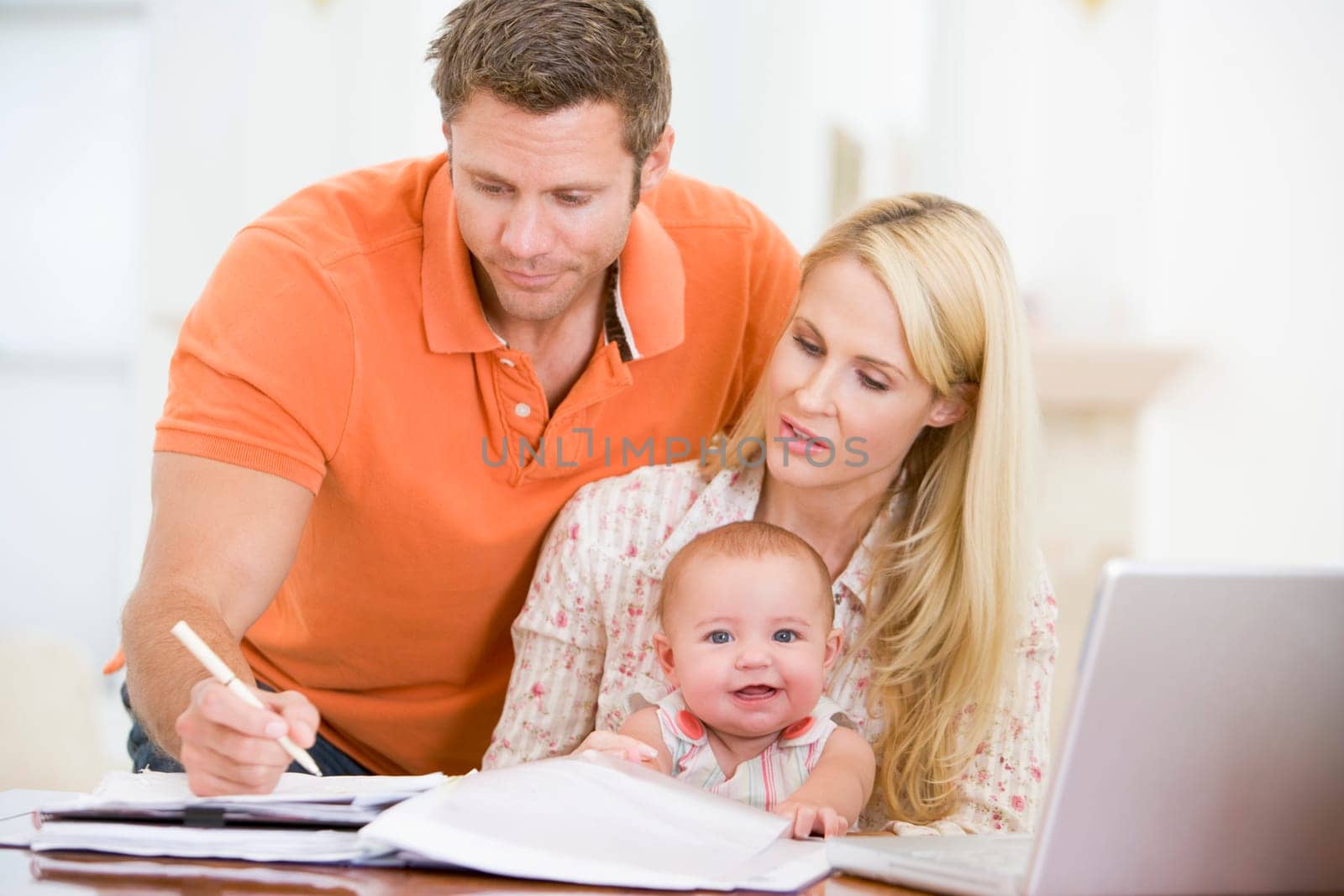 Couple and baby in dining room with laptop