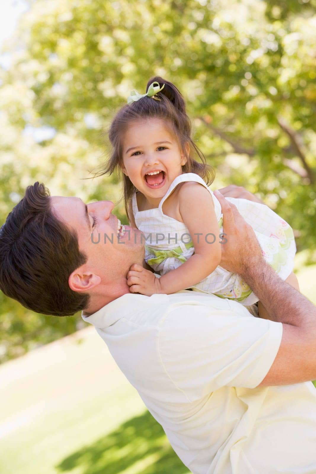 Father holding daughter outdoors smiling