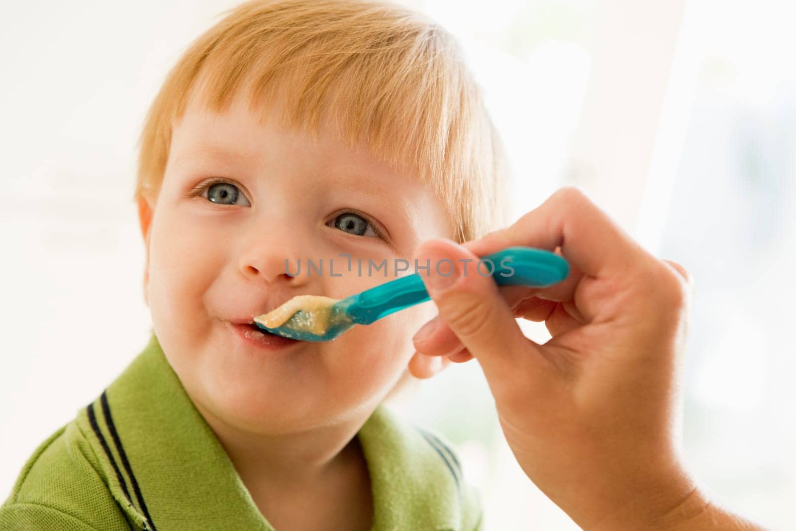 Mother feeding young boy baby food
