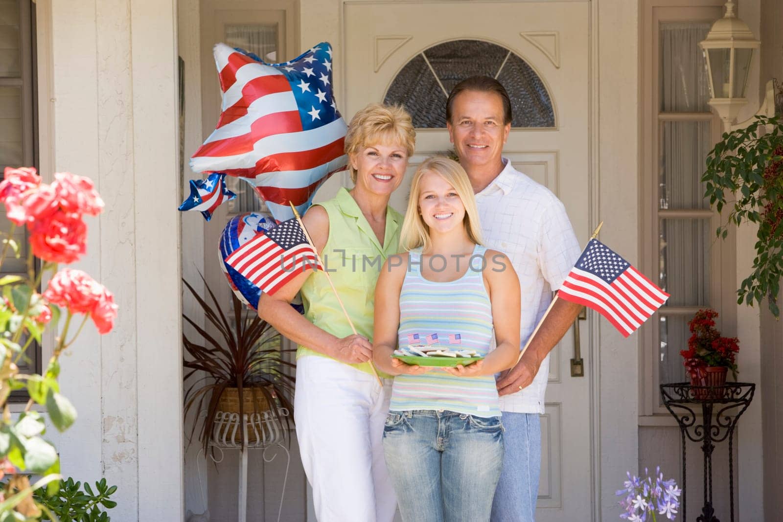 Family at front door on fourth of July with flags and cookies smiling