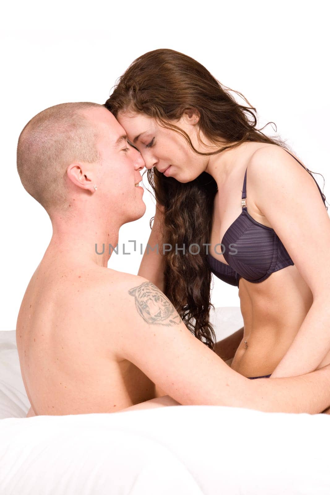 Young couple sitting up in bed fondling