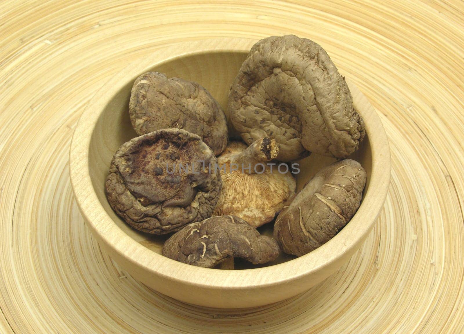 Wooden bowl with shiitake on bamboo plate